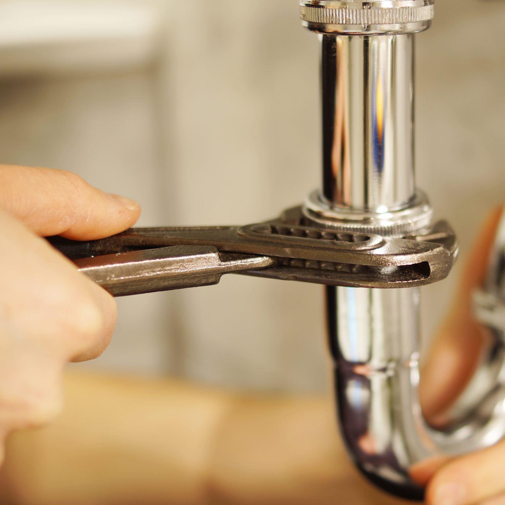 Plumbing repair service. Plumbing repair service. Professional installer with spanner checking pipe.